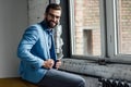stylish smiling man in eyeglasses and blue trendy suit sitting