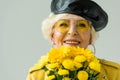 stylish smiling senior woman in yellow leather jacket with bouquet of yellow flowers, Royalty Free Stock Photo