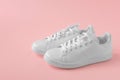 Stylish sneakers. Pair of new white sneakers on pink pastel background. New white leather sneakers sports shoes. Copyspace
