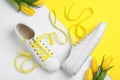 Stylish sneakers with yellow shoe laces and tulips on color background, flat lay Royalty Free Stock Photo