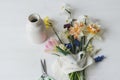 Stylish spring flowers with ribbon and scissors still life. Beautiful daffodils and tulips gentle bouquet on rustic white table Royalty Free Stock Photo