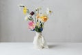 Stylish spring flowers in vase with ribbon still life. Beautiful daffodils and tulips gentle bouquet on rustic white table. Space Royalty Free Stock Photo