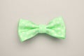 Stylish spring green bow tie with polka dot pattern on light grey background, top view