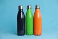 Stylish stainless thermo bottles on light blue background