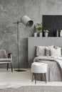 Stylish standing lamp next to a bed in a monochromatic grey bedr