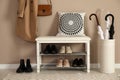 Stylish storage bench with different pairs of shoes near beige wall in hall Royalty Free Stock Photo