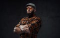 Stylish strong guy with cap and sunglasses poses with crossed arms