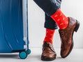 Stylish suitcase, men`s legs and bright socks