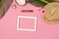 Stylish summer composition with photo frame, green leaves, hat and coconut on a pink pastel background Royalty Free Stock Photo