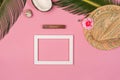 Stylish summer composition with photo frame, green leaves, hat and coconut on a pink pastel background. Royalty Free Stock Photo