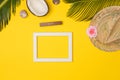 Stylish summer composition with photo frame, green leaves, hat and coconut on a yellow background Royalty Free Stock Photo