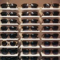 Stylish sunglasses arranged on shelves in glasses store, ready for selection