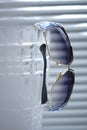 Stylish sunglasses hang on a crystall vase closeup