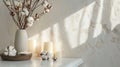 Stylish table with cotton flowers and aroma candles near light wall