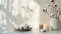 Stylish table with cotton flowers and aroma candles near light wall