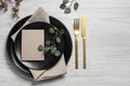 Stylish table setting with cutlery, blank card and eucalyptus leaves, flat lay. Space for text Royalty Free Stock Photo