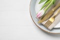 Stylish table setting with cutlery and tulip on white wooden background, top view. Space for text Royalty Free Stock Photo