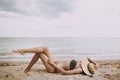 Stylish tanned girl in hat lying on beach. Fashionable young woman covering with straw hat, relaxing on sandy beach near sea. Royalty Free Stock Photo