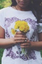 Stylish tanned girl holding bunch of yellow dandelions in her hands Royalty Free Stock Photo