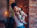 A stylish tattoed blonde female in t-shirt and jeans holds a cute dog. Royalty Free Stock Photo