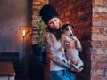 A stylish tattoed blonde female in t-shirt and jeans holds a cute dog. Royalty Free Stock Photo