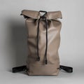 Stylish taupe rolltop backpack with black drawstrings against a neutral backdrop Royalty Free Stock Photo