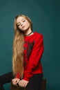 Stylish teen, beautiful young model girl with long blonde hair in black jeans and in fashionable red sweatshirt posing Royalty Free Stock Photo