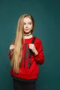 Stylish teen, beautiful young model girl with long blonde hair, posing at studio in jeans and red sweatshirt Royalty Free Stock Photo