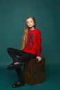 Stylish teen, beautiful young model girl with long blonde hair, posing at studio in jeans and red sweatshirt Royalty Free Stock Photo