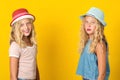 Stylish teenage girls wearing summer hats over yellow background. .Summer fashion, sales, lifestyle Royalty Free Stock Photo