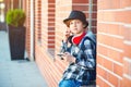 Stylish teenager boy with headphones and mobile phone outdoors. Cute boy with headphones listens to the music. Schoolboy plays