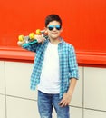 Stylish teenager boy wearing a checkered shirt and sunglasses with skateboard in city Royalty Free Stock Photo