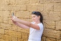 Stylish teenager girl takes a selfie in city over stone wall background. Royalty Free Stock Photo