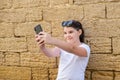 Stylish teenager girl takes a selfie in city over stone wall background. Royalty Free Stock Photo