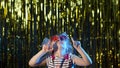 Stylish teenager kid girl standing on backlit blue neon lights and points at blank space, agree sign