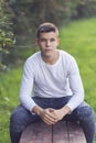 Stylish teenager sitting on a wooden bench on a city park Royalty Free Stock Photo