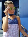 Stylish teenager in sunglasses against a blue wall