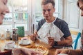 Stylish teenager wearing napkin holding knife and fork ready to eat pizza sitting against window at restaurant Royalty Free Stock Photo