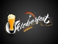 Stylish text Oktoberfest Beer Festival with wine glass, sausage fork and wheat on black background. Royalty Free Stock Photo