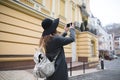 A stylish tourist girl takes a photo of the old town on his own smartphone.