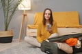 Stylish tourist lifestyle. Packed for a journey. Caucasian young adult woman packing suitcase at home using mobile phone booking Royalty Free Stock Photo