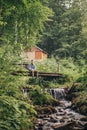 Stylish traveler man sitting on wooden bridge at river in sunny Royalty Free Stock Photo