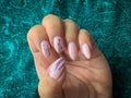 Stylish trendy female pink manicure. Pink manicure with with black geometric pattern on almond-shaped nails on a green background