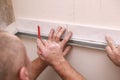 Stylish trendy white ceramic tiles on the kitchen wall. Hands in the process of laying white rectangular tiles on the Royalty Free Stock Photo