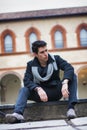 Stylish trendy young man sitting outdoor in old historical building