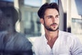 Stylish trendy young man standing outdoor against window