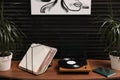 Stylish turntable with vinyl discs on table in room