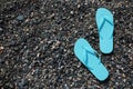 Stylish turquoise flip lops on pebble beach, flat lay. Space for text