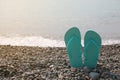 Stylish turquoise flip lops on pebble beach near sea, closeup. Space for text