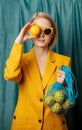 Stylish ukrainian woman in yellow sunglasses and jacket with lemons in net bag Royalty Free Stock Photo